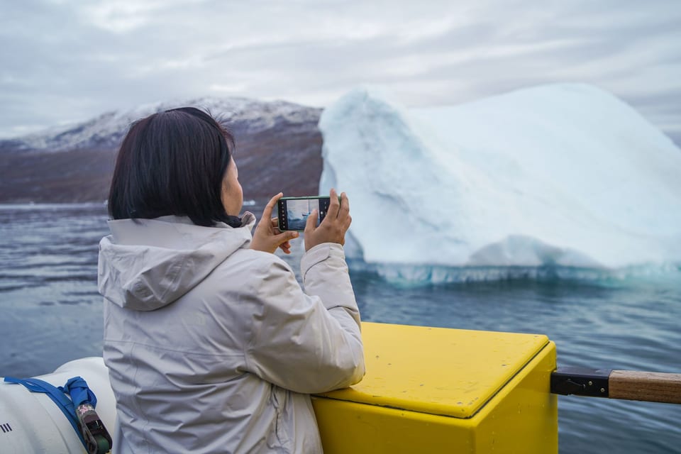 ผู้เดินทางถ่ายภาพภูเขาน้ำแข็งจากเรือในกรีนแลนด์